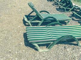 vacation by the sea on the beach. on the pebbly ground there are sun loungers for sunbathing tourists. on sunbeds mattresses and green fabric photo