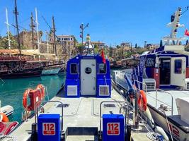 un barco azul navega en el mar para que los turistas viajen. a bordo se cuelgan círculos de natación naranjas. puerta de la cabina con una pequeña ventana redonda de vidrio foto