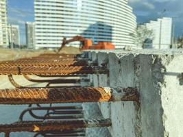 concrete block with rusty rebar sticking out inside. fasteners for the construction of concrete high houses. blocks on the background of high-rise buildings photo