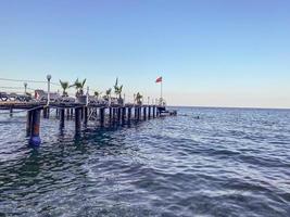 hot, tropical country with sea and mountains. on the beach there are pebbles and small stones. high wooden diving pontoon photo