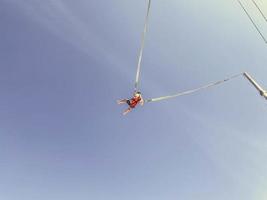 catapult on top of the mountain. entertainment for tourists, active recreation. jump up on a huge elastic band, a man in equipment, a protective suit flies on a catapult photo