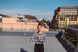 Woman doing yoga exercises on house roof in early morning photo