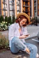 Young lady sitting stairs typing device outside urban city street photo
