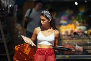 Young woman chooses meat in a grocery store photo