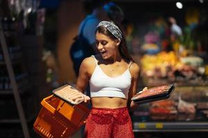 Young woman chooses meat in a grocery store photo