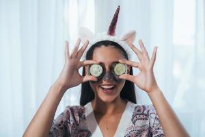 Funny smiling Spa Woman with fresh Facial Mask hold cucumbers. photo