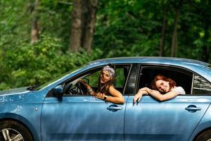 Two girlfriends fool around and laughing together in a car photo