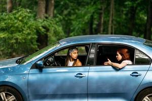 Two girlfriends fool around and laughing together in a car photo