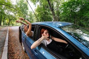 Two girlfriends fool around and laughing together in a car photo