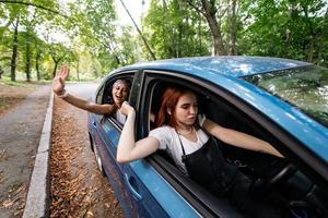 Two girlfriends fool around and laughing together in a car photo