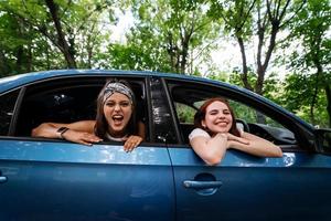 Two girlfriends fool around and laughing together in a car photo