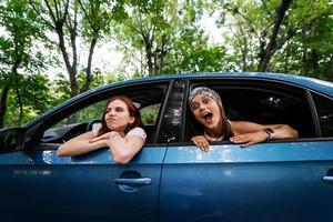 Two girlfriends fool around and laughing together in a car photo