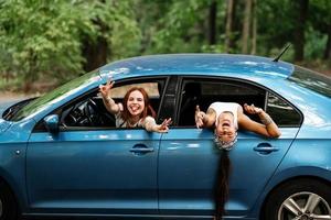 Two girlfriends fool around and laughing together in a car photo