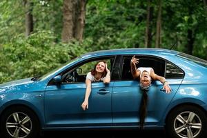 Two girlfriends fool around and laughing together in a car photo