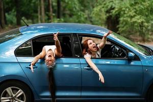 Two girlfriends fool around and laughing together in a car photo