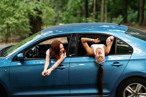 Two girlfriends fool around and laughing together in a car photo