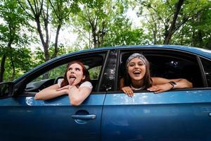 Two girlfriends fool around and laughing together in a car photo