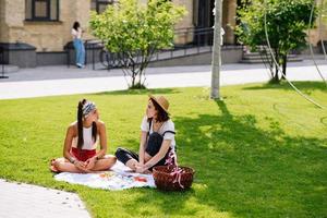 Two women having picnic together, sitting on the plaid photo