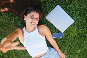 Young fit attractive woman lying on green lawn park. photo