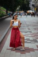 Woman in the street drinking morning coffee and use smartphone. photo