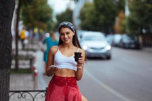 Woman in the street drinking morning coffee and use smartphone. photo