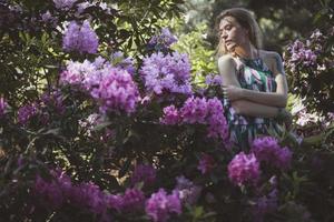 dama abrazándose cerca de arbustos rosados en flor fotografía escénica foto