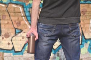 artista de graffiti con una lata de aerosol en la mano. vista trasera foto