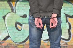 Close-up of male hands, handcuffed against a graffiti background photo