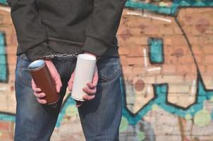 A rear view of an arrested street artist in handcuffs with aeros photo