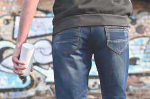 Graffiti artist with a spray can in his hand. Back view photo