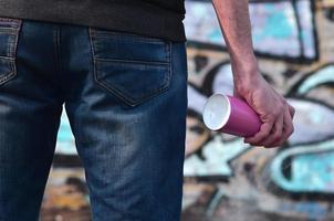 Rear view of a guy drawing a wall with aerosol paint photo