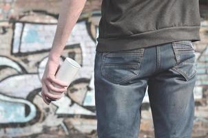 Graffiti artist with a spray can in his hand. Back view photo