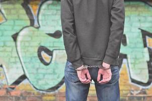 Close-up of male hands, handcuffed against a graffiti background photo