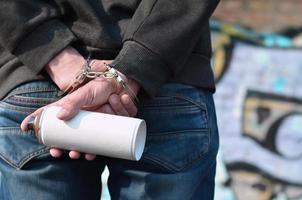 A rear view of an arrested street artist in handcuffs with aeros photo