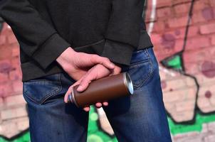 Rear view of a guy drawing a wall with aerosol paint photo