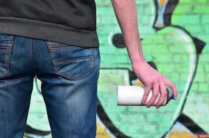 Graffiti artist with a spray can in his hand. Back view photo