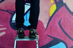 A young graffiti artist paints a new graffiti on the wall. Photo of the process of drawing a graffiti on a wall close-up. The concept of street art and illegal vandalism