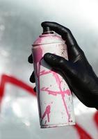 A hand with a spray can that draws a new graffiti on the wall. Photo of the process of drawing a graffiti on a metal wall. The concept of street art and illegal vandalism