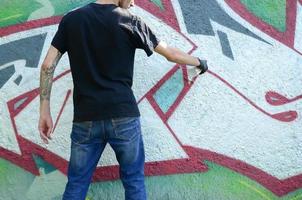 un joven gamberro pinta graffiti en una pared de hormigón. concepto de vandalismo ilegal. arte callejero foto