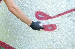 A hand in black gloves paints graffiti on a concrete wall. Illegal vandalism concept. Street art photo
