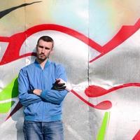 The graffiti artist with spray can poses against the background of a colorful painted wall. Street art concept photo