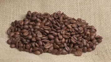 Coffee beans falling on jute background at slow motion video