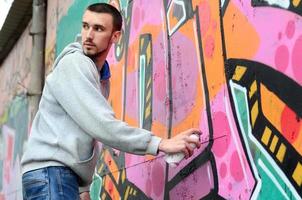 A young graffiti artist looks around while drawing. Vandal tries photo