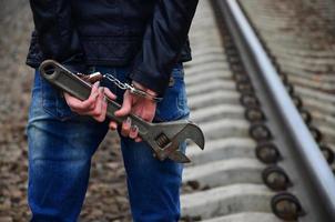 la chica esposada con la llave ajustable en el ferrocarril foto