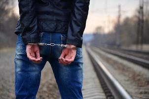 Girl in handcuffs on the background of a railway track photo