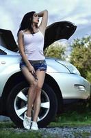 Young and sexy girl with spanner close to a silver car with an o photo