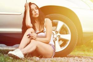 Young and sexy girl with spanner close to a silver car with an o photo