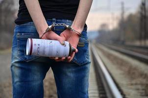 Girl in handcuffs with spraycan on the background of a railway t photo