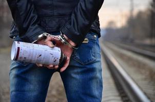 Girl in handcuffs with spraycan on the background of a railway t photo