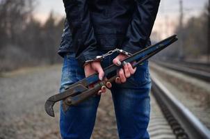 The girl in handcuffs with the pipe wrench on the railway track photo